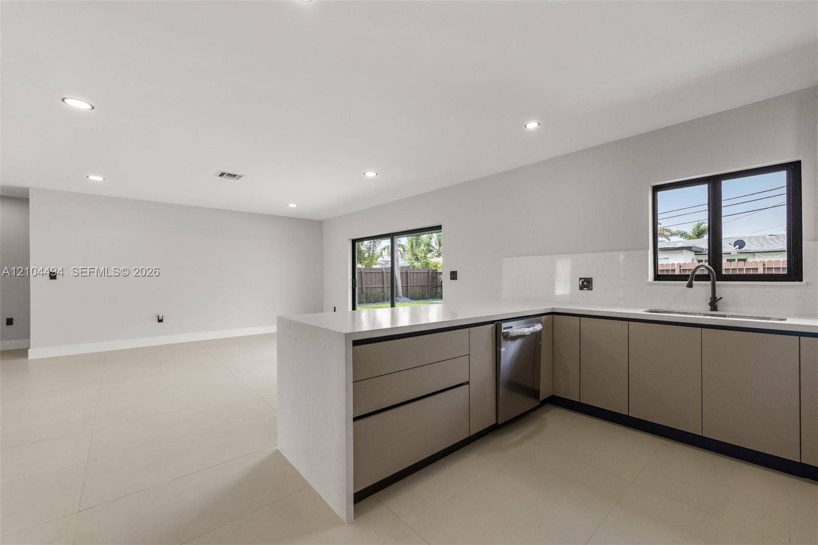 711 NW 8th Avenue, Dania Beach, FL 33004 Kitchen featuring flat-panel cabinetry, light-toned stone-finish countertops, recessed ceiling lighting, large-format tile flooring, and matte black plumbing fixtures