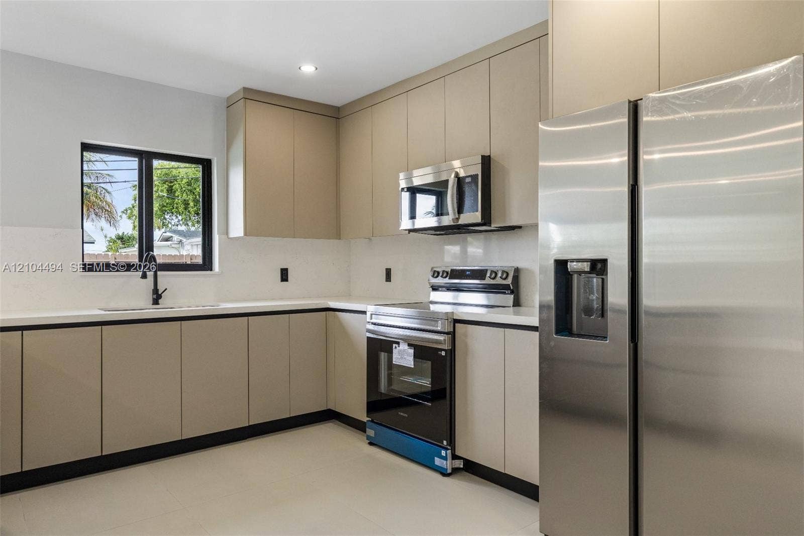 711 NW 8th Avenue, Dania Beach, FL 33004 Kitchen featuring flat-panel cabinetry, quartz countertops, stainless steel appliances, and a matte black faucet
