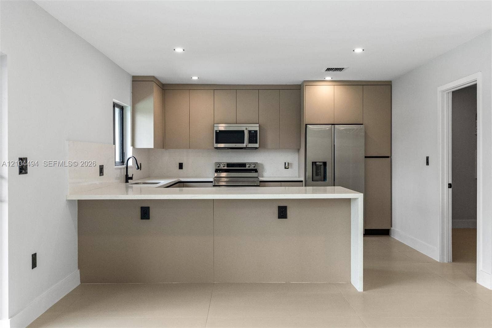711 NW 8th Avenue, Dania Beach, FL 33004 Kitchen featuring flat-panel cabinetry, quartz countertops with a waterfall edge, stainless steel appliances, recessed lighting, and large-format tile flooring