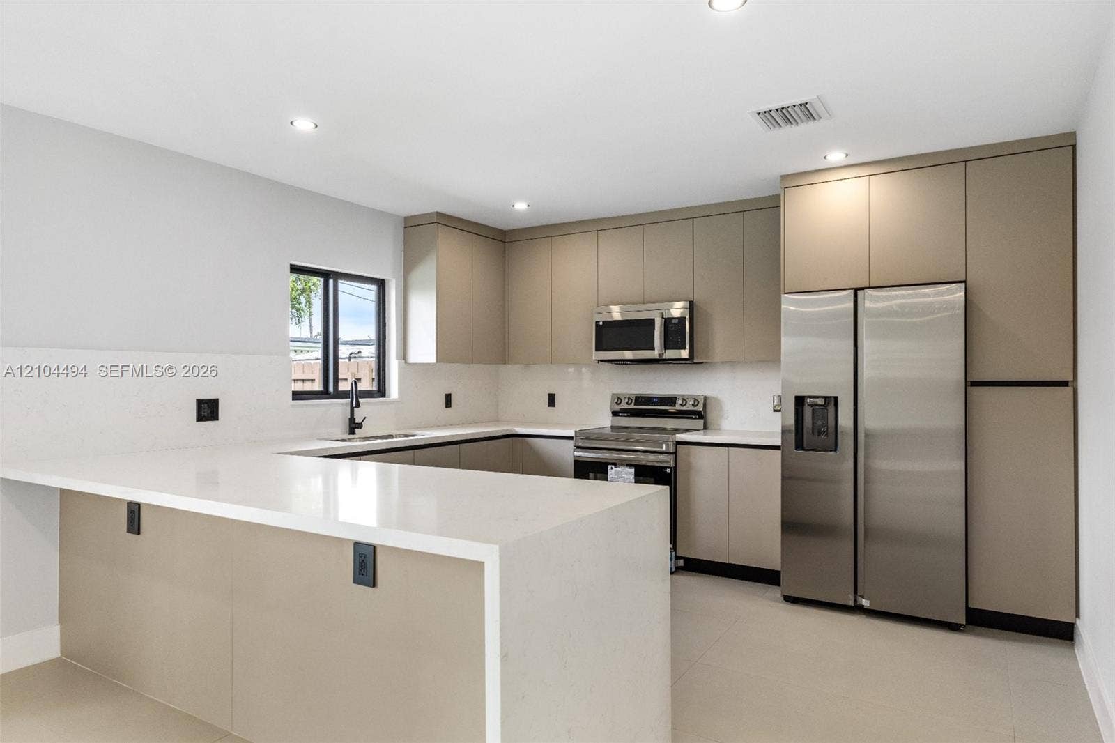 711 NW 8th Avenue, Dania Beach, FL 33004 Kitchen featuring flat-panel cabinetry, quartz countertops with a waterfall edge, stainless steel appliances, and recessed lighting