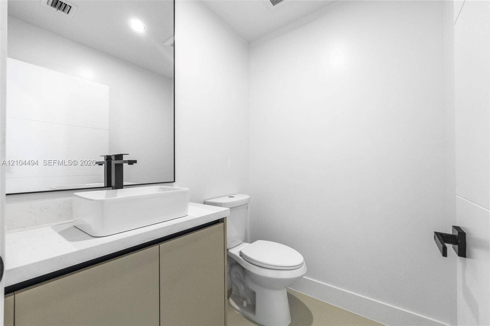 711 NW 8th Avenue, Dania Beach, FL 33004 Vanity featuring a rectangular vessel sink, quartz countertop, matte black faucet, and frameless mirror, paired with a two-piece toilet and matching matte black hardware