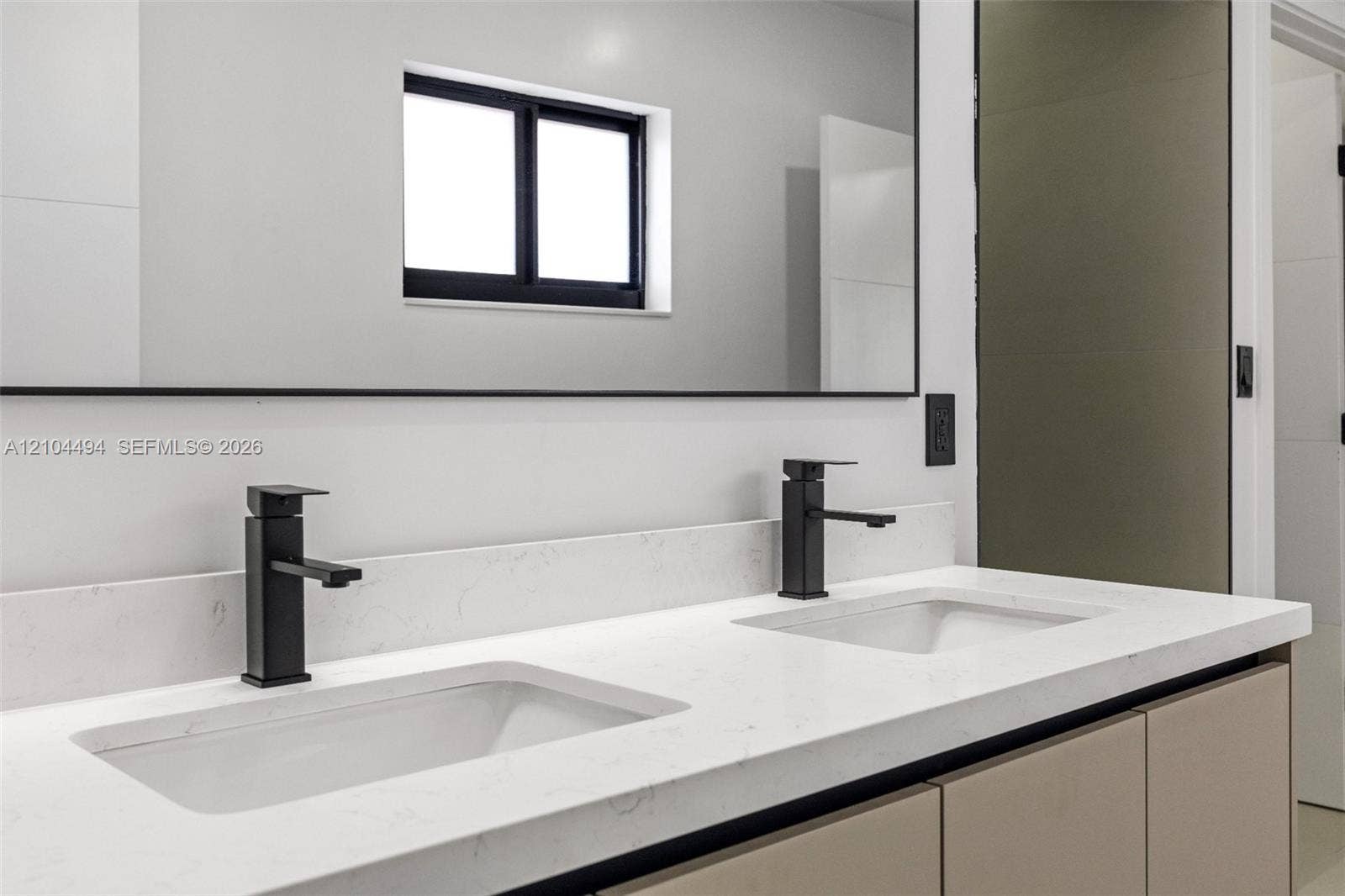 711 NW 8th Avenue, Dania Beach, FL 33004 Dual-sink vanity featuring a light-toned countertop, undermount basins, matte black hardware, and an expansive wall-to-wall mirror