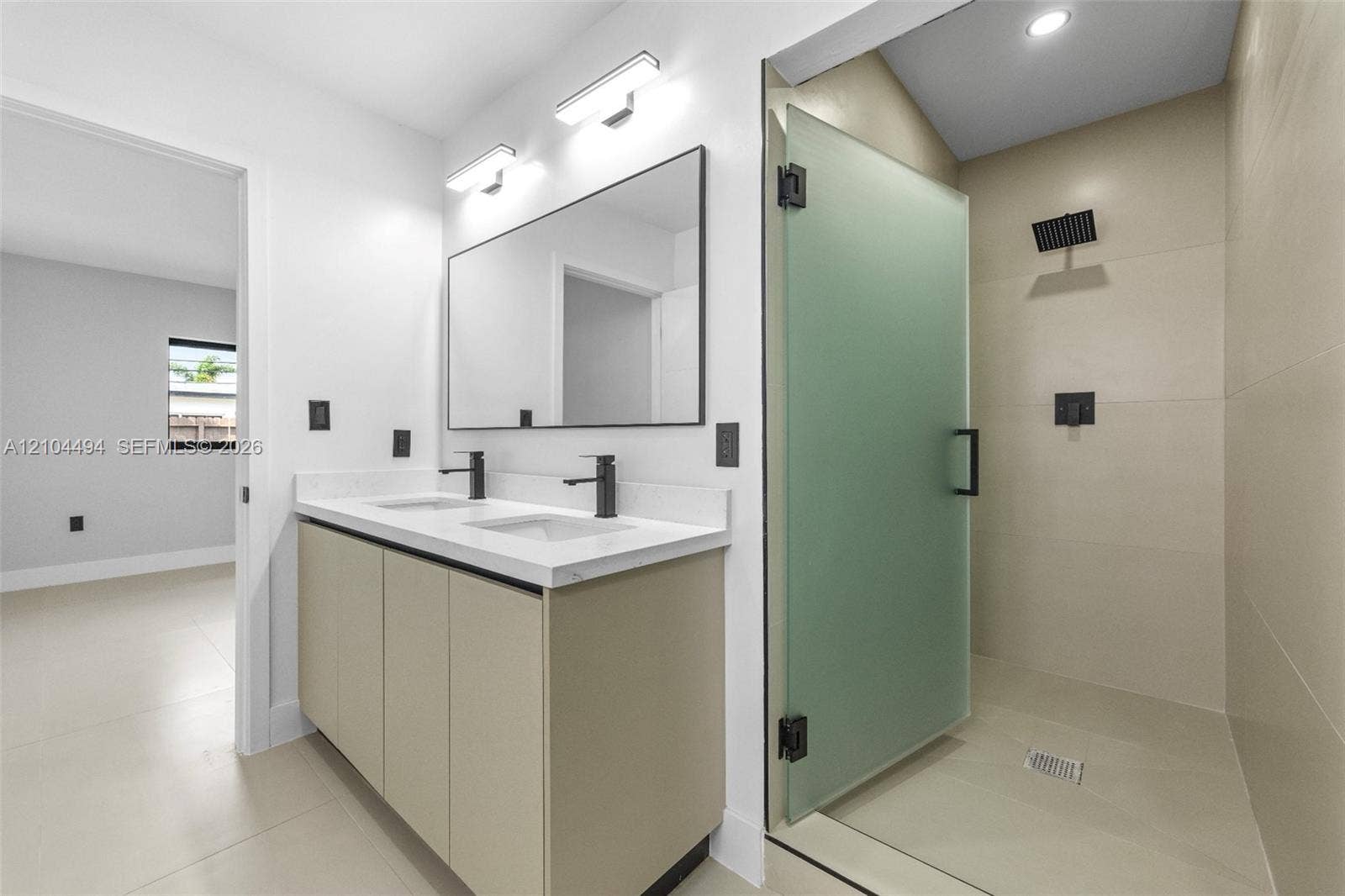 711 NW 8th Avenue, Dania Beach, FL 33004 Double vanity with white solid-surface countertop and matte black faucets, paired with a frameless walk-in shower featuring frosted glass, large-format tile surround, and matte black rainfall showerhead