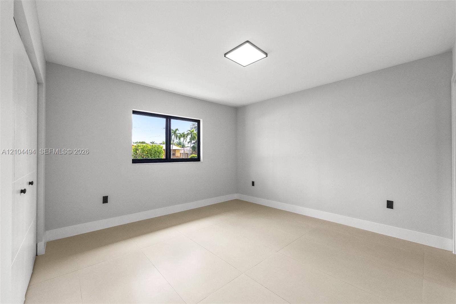 711 NW 8th Avenue, Dania Beach, FL 33004 Neutral-toned interior featuring large-format tile flooring, recessed square ceiling lighting, and a window with a black frame