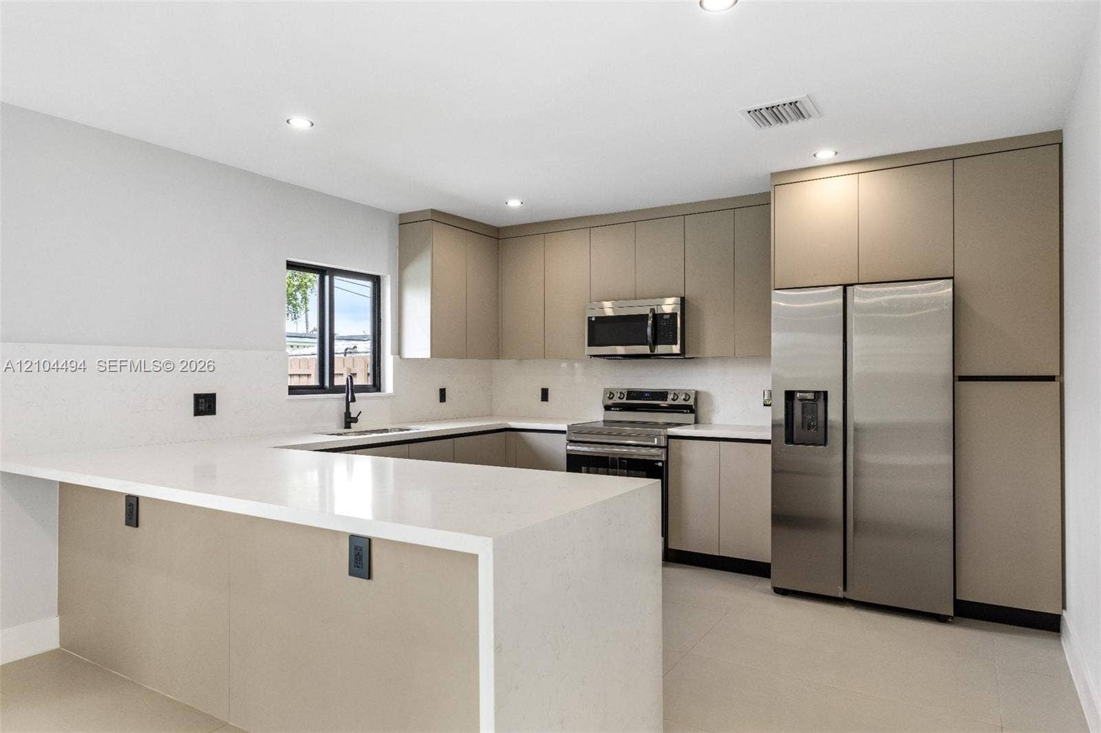 711 NW 8th Avenue, Dania Beach, FL 33004 Kitchen featuring flat-panel cabinetry, quartz countertops, tile backsplash, stainless steel appliances, and recessed lighting