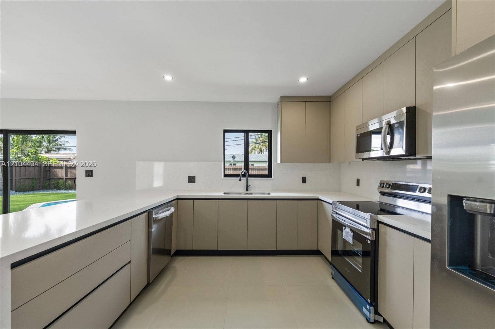 711 NW 8th Avenue, Dania Beach, FL 33004 Kitchen featuring flat-panel cabinetry, quartz countertops, solid-surface backsplash, stainless steel appliances, and recessed lighting