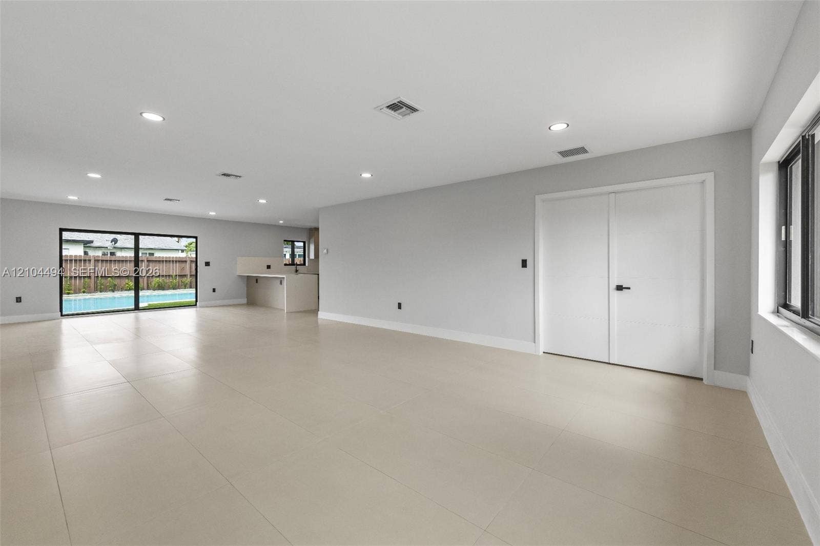 711 NW 8th Avenue, Dania Beach, FL 33004 Open interior featuring large-format neutral tile flooring, recessed ceiling lighting, a built-in counter area, and sliding glass doors