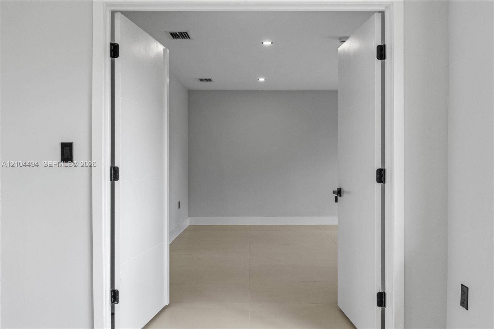 711 NW 8th Avenue, Dania Beach, FL 33004 Double interior doors featuring matte black hardware, recessed ceiling lighting, and neutral large-format tile flooring