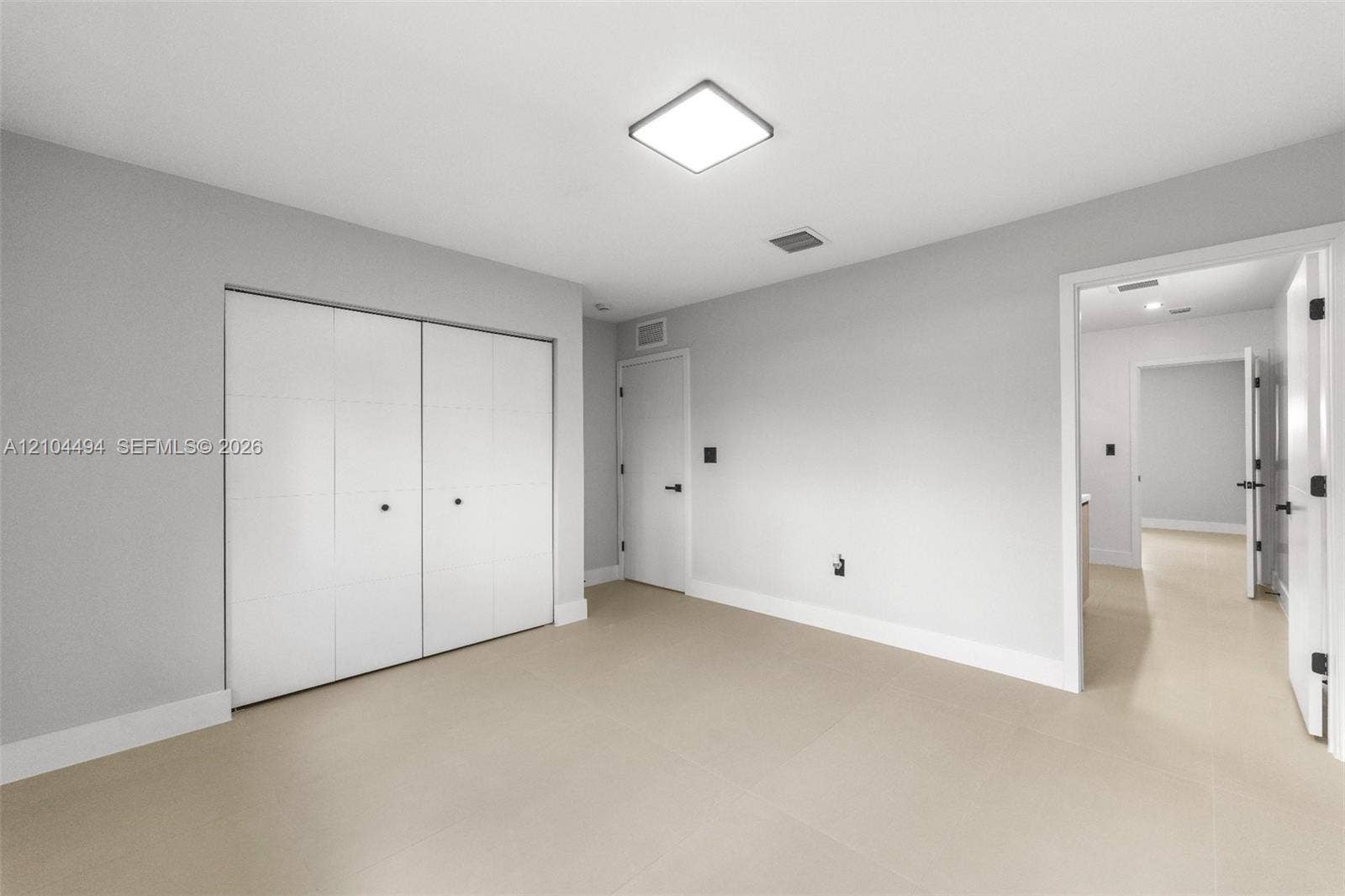711 NW 8th Avenue, Dania Beach, FL 33004 Neutral-toned room featuring large-format tile flooring, recessed square ceiling lighting, white flush-panel closet doors, and matte black door hardware