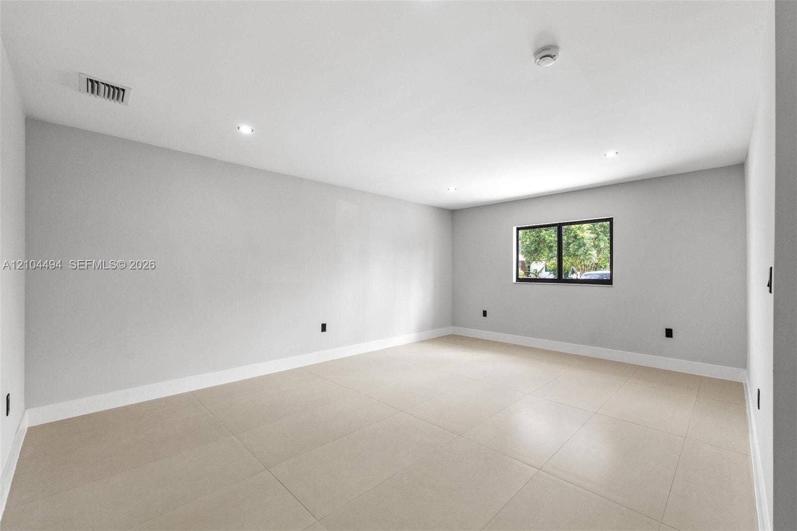 711 NW 8th Avenue, Dania Beach, FL 33004 Interior space featuring neutral wall tones, large-format tile flooring, recessed ceiling lighting, and a single window with a black frame