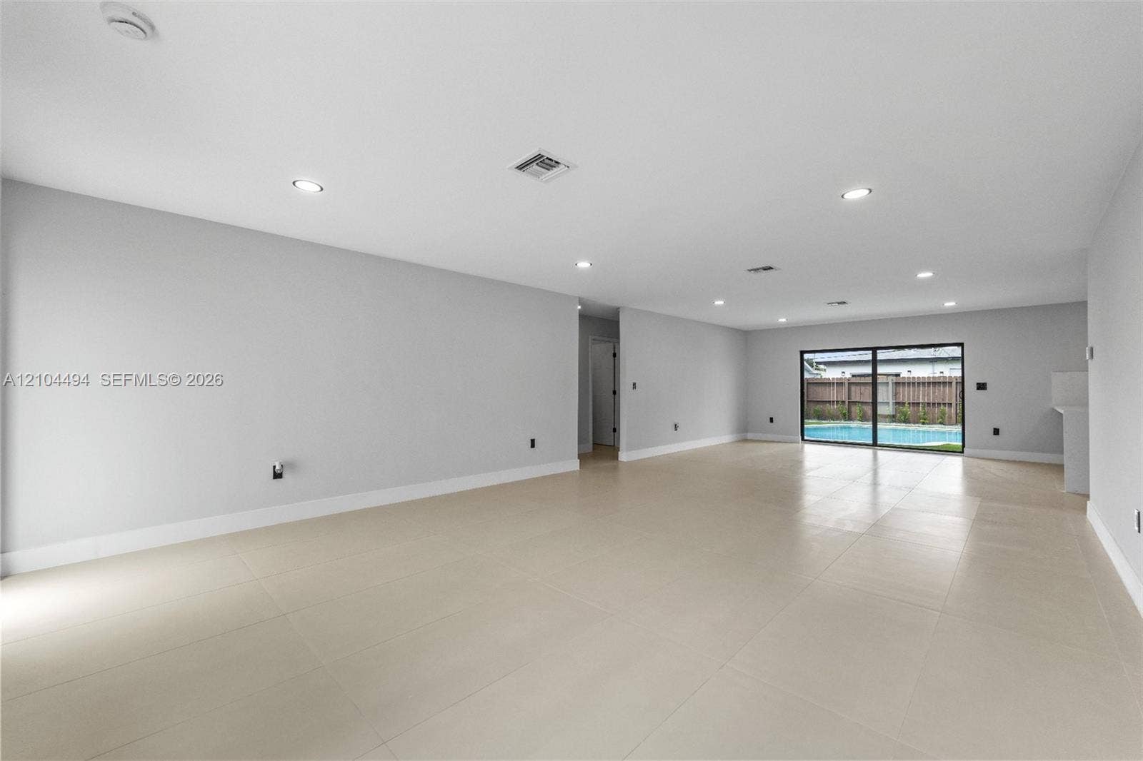711 NW 8th Avenue, Dania Beach, FL 33004 Open-concept interior featuring large-format tile flooring, recessed lighting, and expansive glass sliding doors