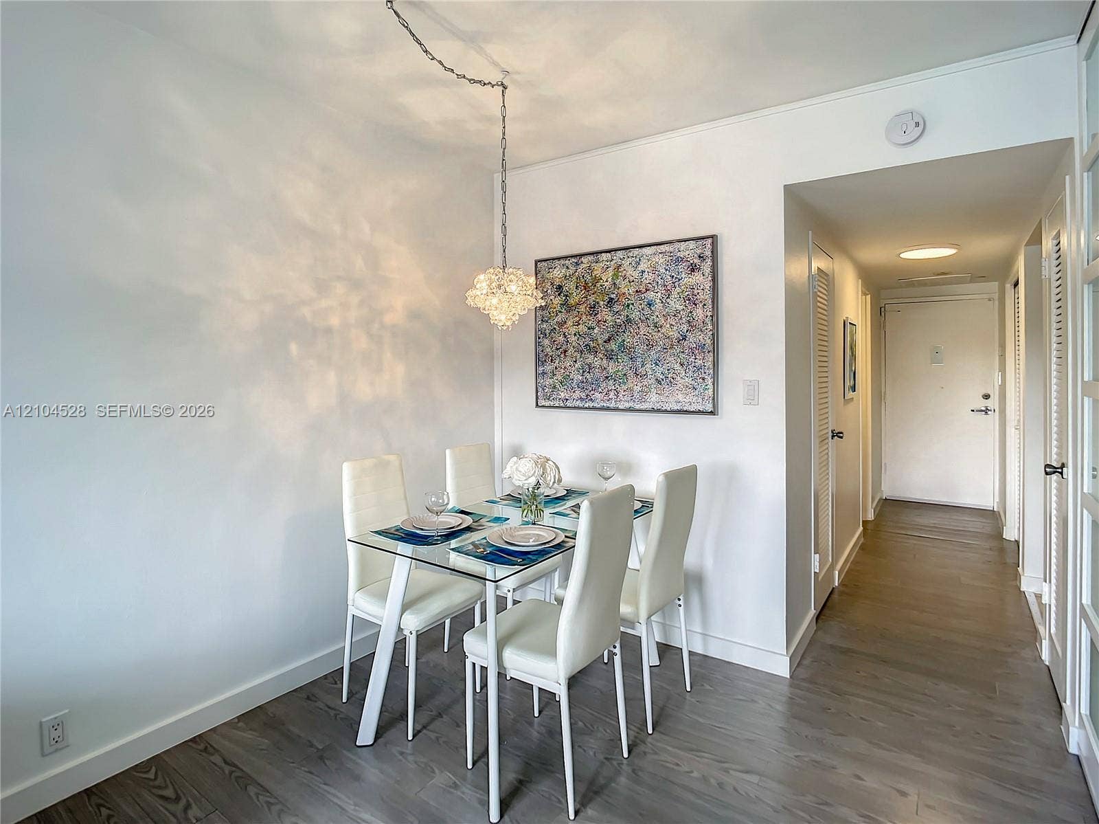 Wood-finish flooring, crisp white walls, and a decorative crystal-style pendant light fixture with a chain suspension