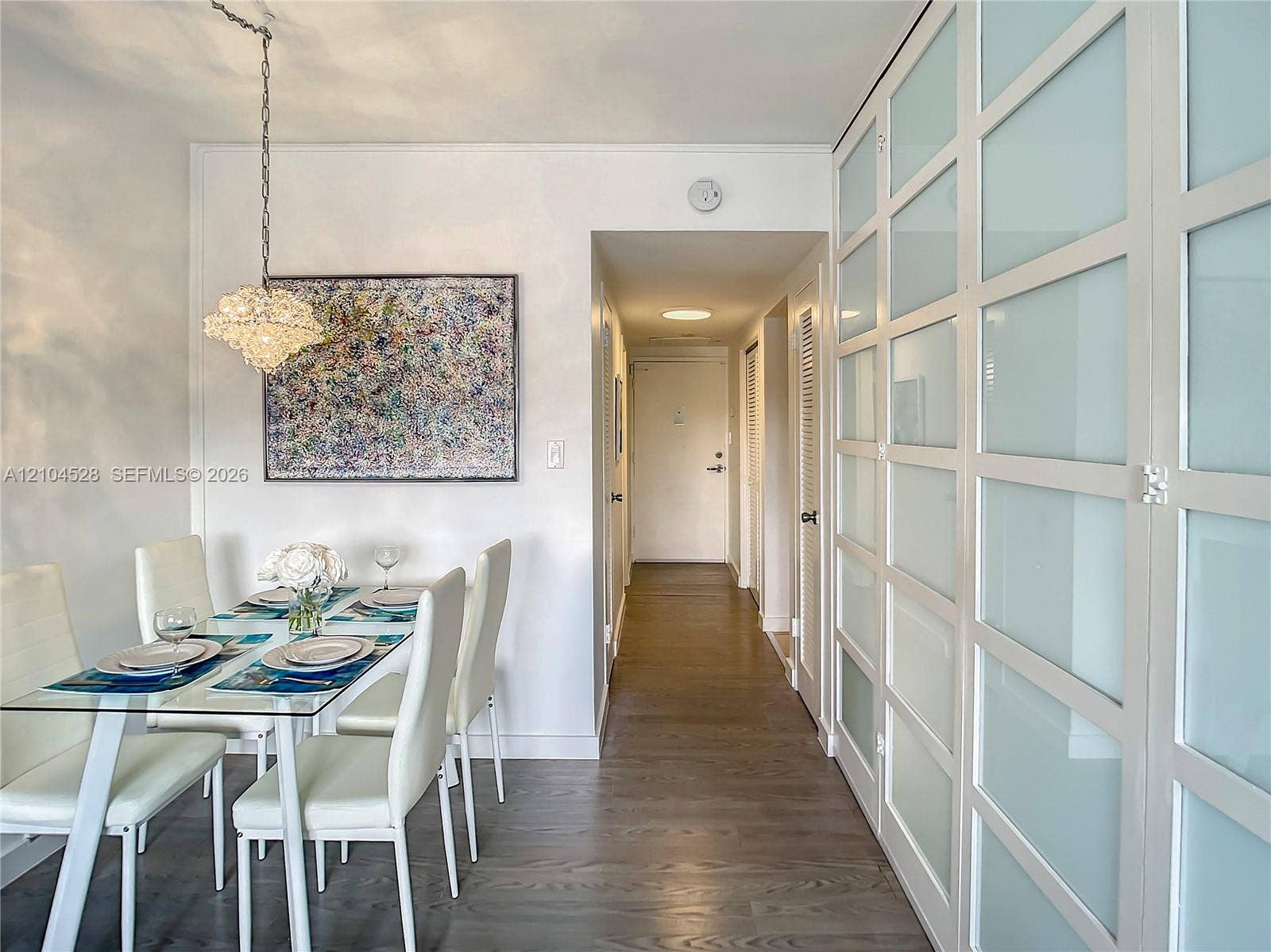 Full-height built-in cabinetry featuring frosted glass panel doors, wood-finish flooring, and a decorative hanging pendant light fixture