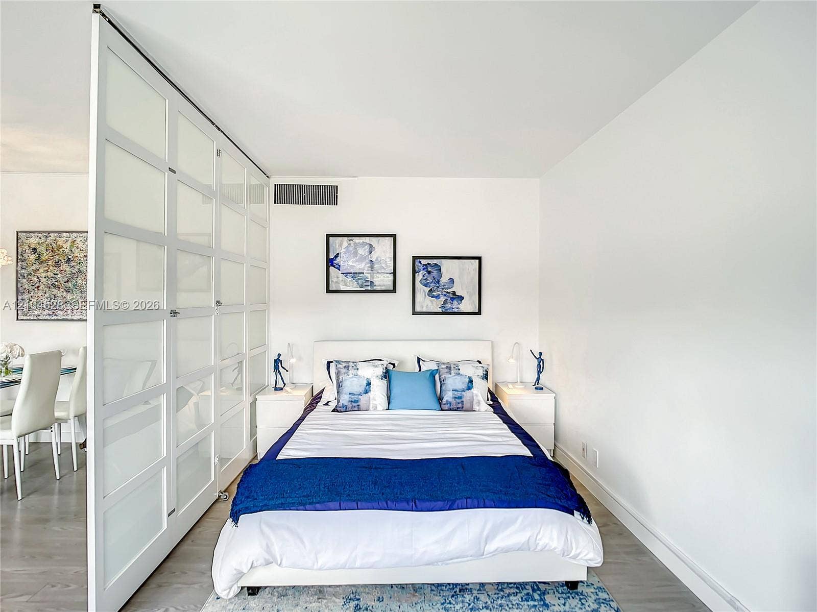 Floor-to-ceiling glass panel room divider with white frames and light-tone wood-finish flooring