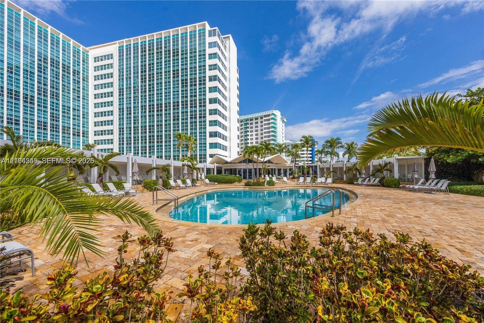 5055 Collins Avenue, #12F, Miami Beach, FL 33140 Resort-style pool area with a curvilinear swimming pool, paver deck, and multiple cabanas