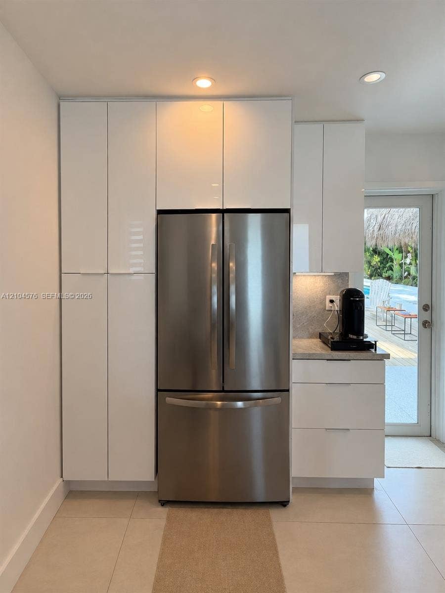 9755 SW 54th Street, Miami, Miami, FL 33165 High-gloss white cabinetry, stainless steel French-door refrigerator, stone-surface countertop, recessed ceiling lighting, and large-format tile flooring