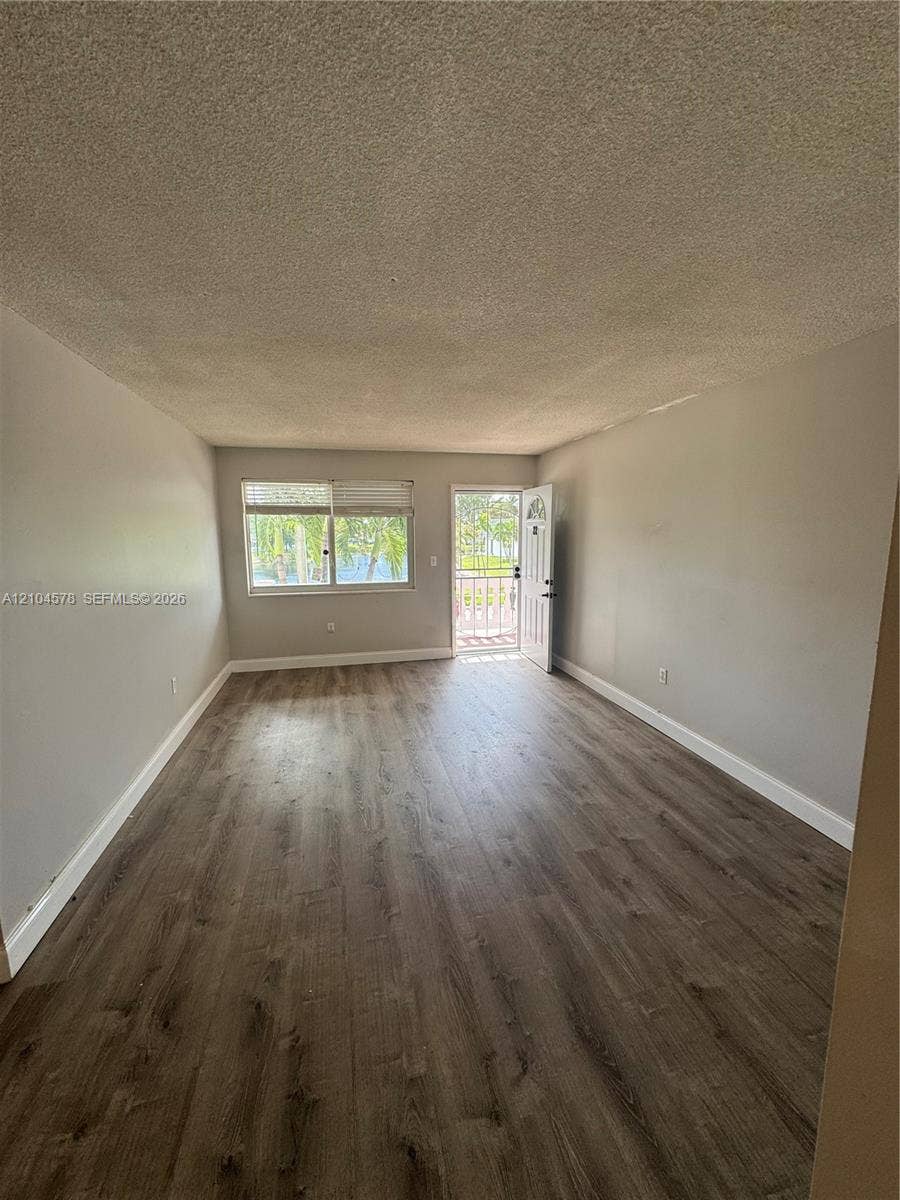20320 NE 2nd Avenue, #22, Miami Gardens, Miami Gardens, FL 33179 Interior space featuring wood-finish flooring, neutral wall paint, and natural light from a window and door