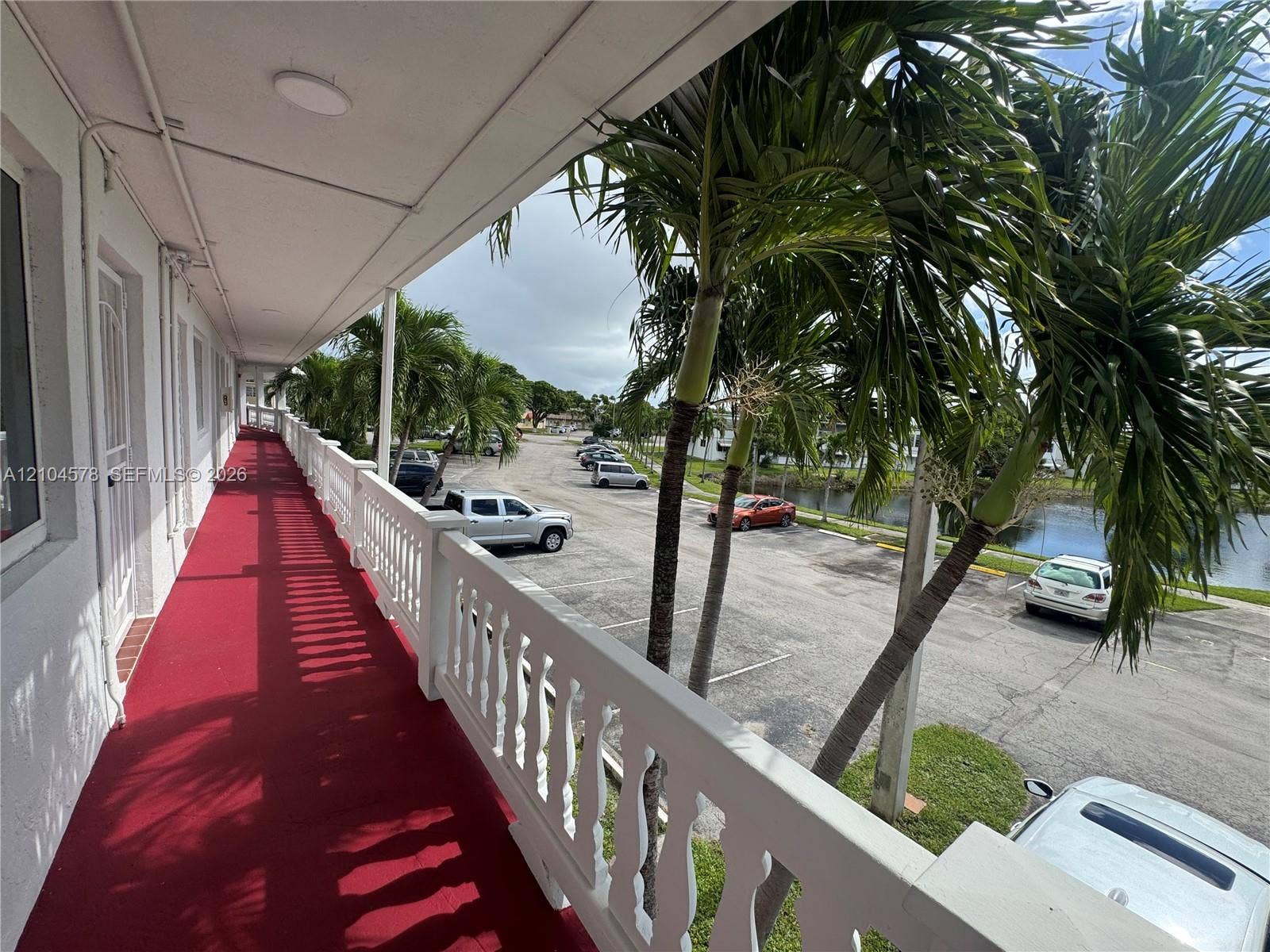 20320 NE 2nd Avenue, #22, Miami Gardens, Miami Gardens, FL 33179 Covered exterior walkway featuring a red floor surface and a white balustrade railing