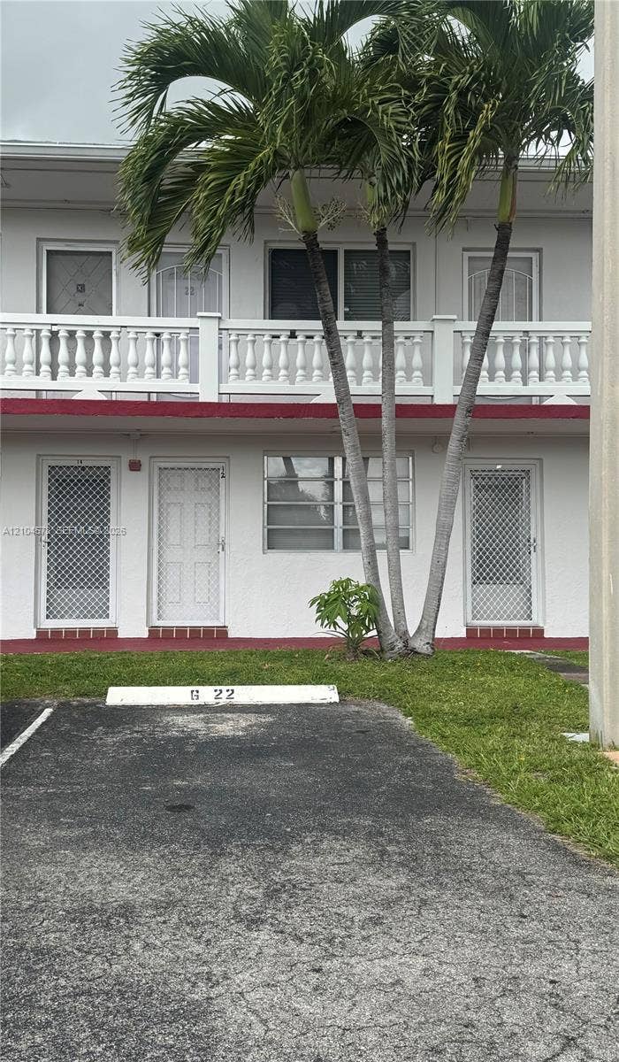 20320 NE 2nd Avenue, #22, Miami Gardens, Miami Gardens, FL 33179 Two-story exterior featuring white stucco finish, second-level balustrade balcony, and assigned surface parking space