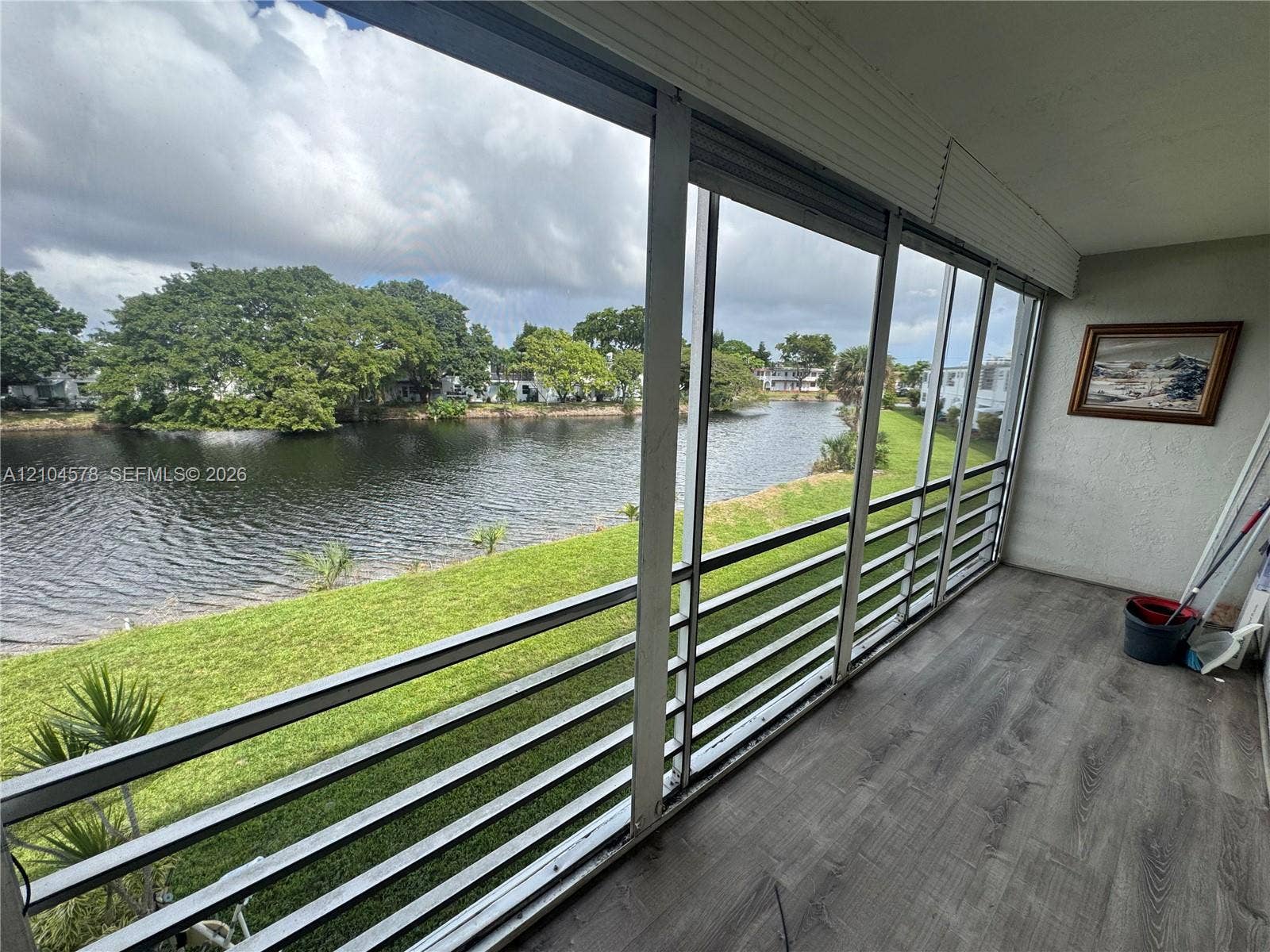 20320 NE 2nd Avenue, #22, Miami Gardens, Miami Gardens, FL 33179 Screened-in porch featuring horizontal metal railings, wood-finish flooring, and direct exposure to a water canal