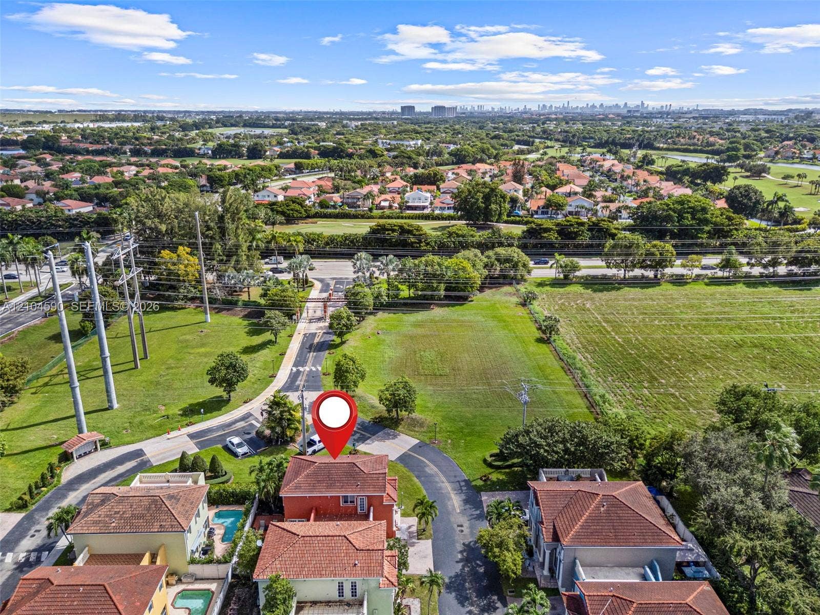 Aerial perspective featuring a multi-story residence with a clay tile roof, situated on a corner lot with paved access