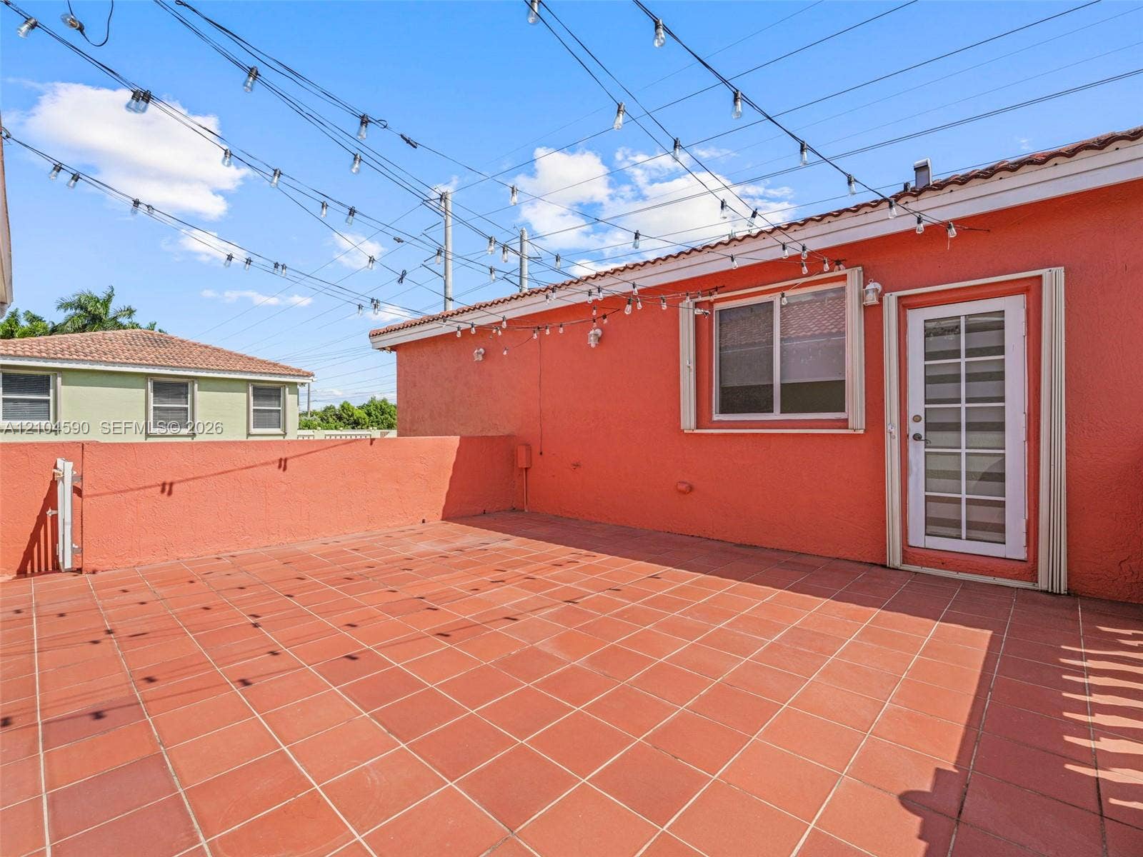 Outdoor terrace featuring terracotta-style tile flooring, stucco wall perimeter, and a multi-pane glass entry door
