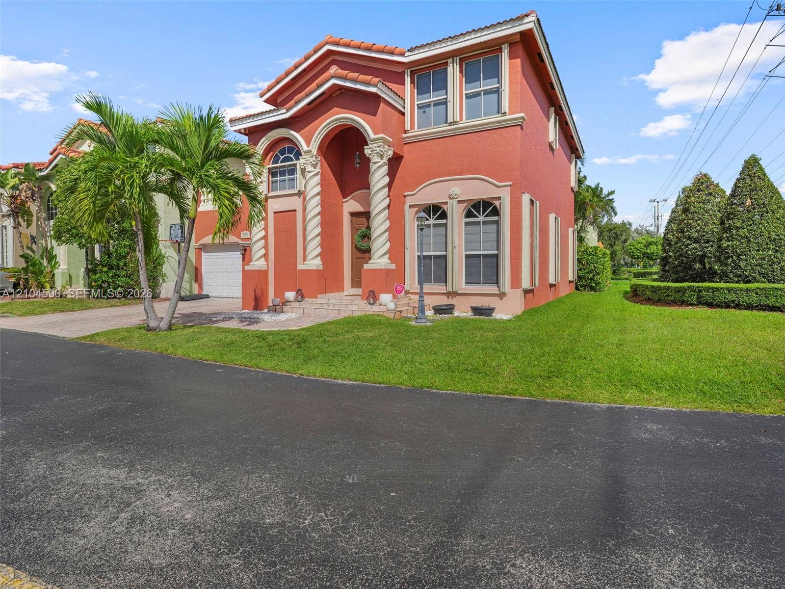 Two-story Mediterranean-style exterior featuring decorative spiral columns, arched window detailing, a tiled roof, and a paved walkway