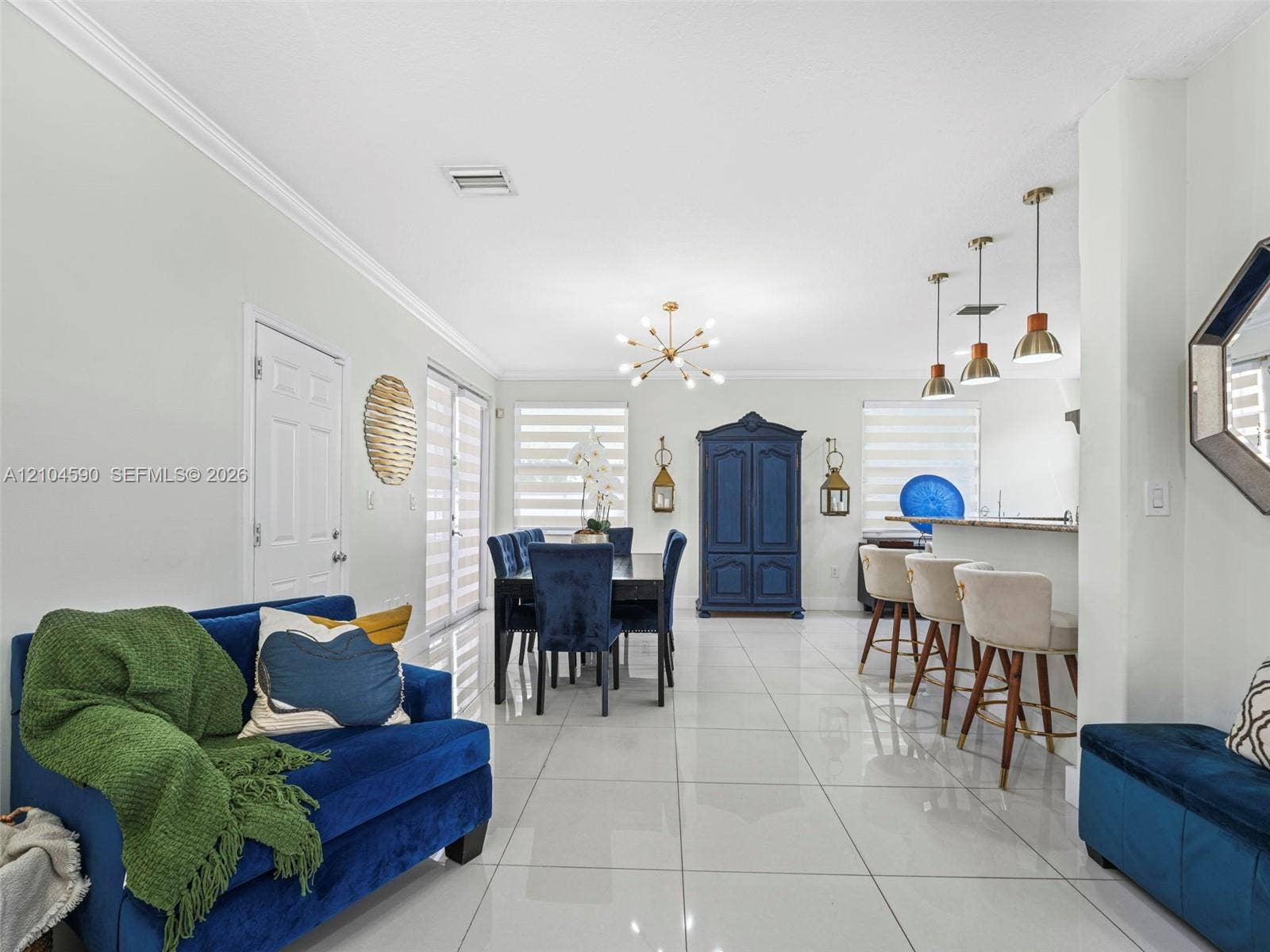 Large-format tile flooring, recessed lighting, crown molding, tiered kitchen peninsula, and multi-light chandelier fixture
