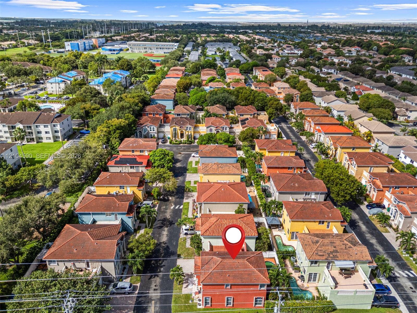 Aerial perspective showcasing a multi-story residence with a clay tile roof, stucco exterior, and private swimming pool