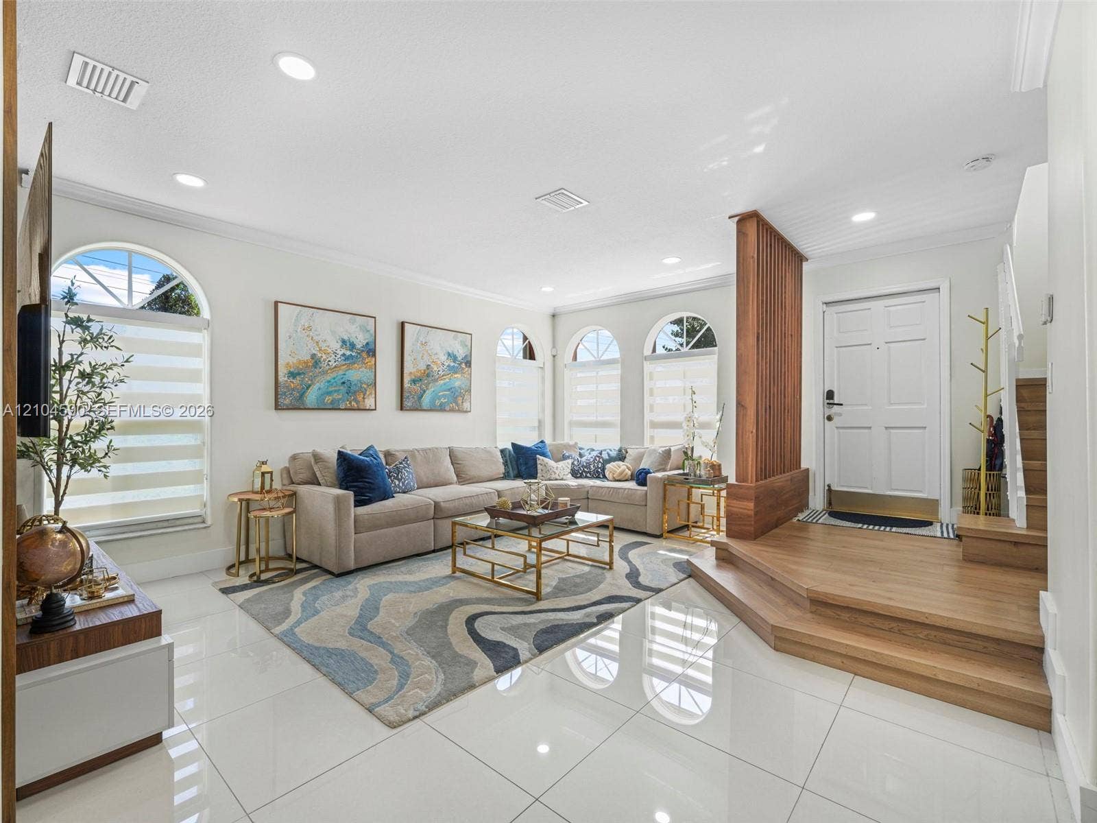 Polished porcelain tile flooring, wood-finish raised entryway platform with integrated slat room divider, recessed ceiling lighting, and multiple arched windows