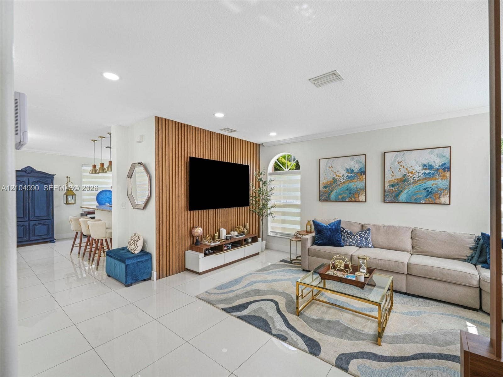 Living area featuring polished tile flooring, a vertical wood-slat accent wall, recessed lighting, and an arched window
