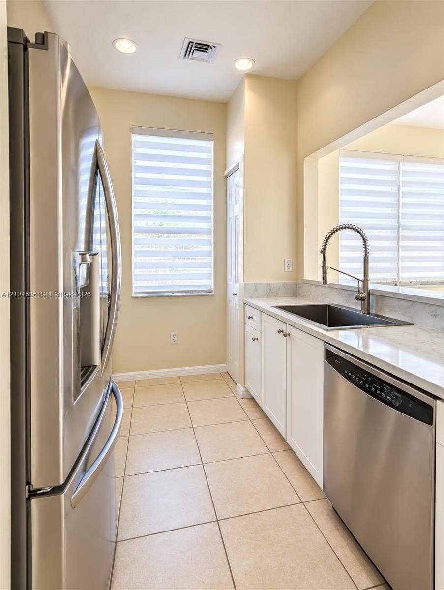10968 SW 236th Terrace, Homestead, Homestead, FL 33032 Kitchen featuring stainless steel appliances, white cabinetry, solid surface countertops, a deep-basin sink with a pull-down faucet, and ceramic tile flooring