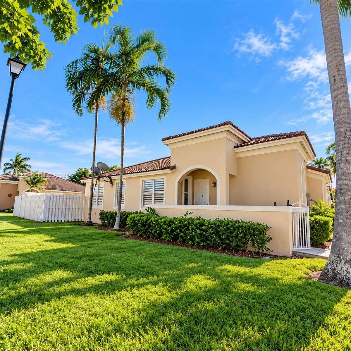 10968 SW 236th Terrace, Homestead, Homestead, FL 33032 Stucco exterior featuring a tiled roof, arched entryway, white shuttered windows, and a walled courtyard