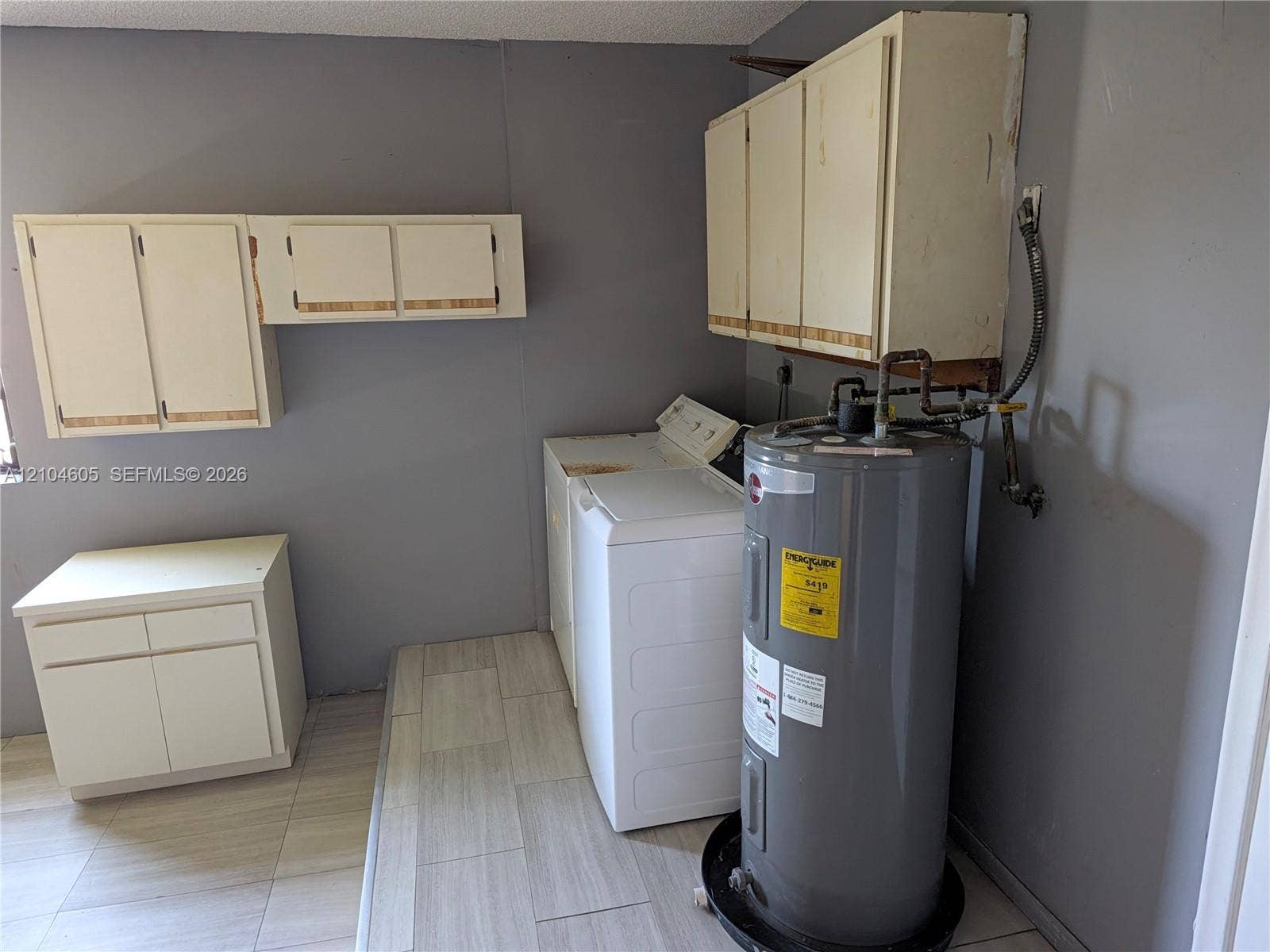 Utility space featuring light-toned cabinetry, neutral wall-finish, and tile flooring