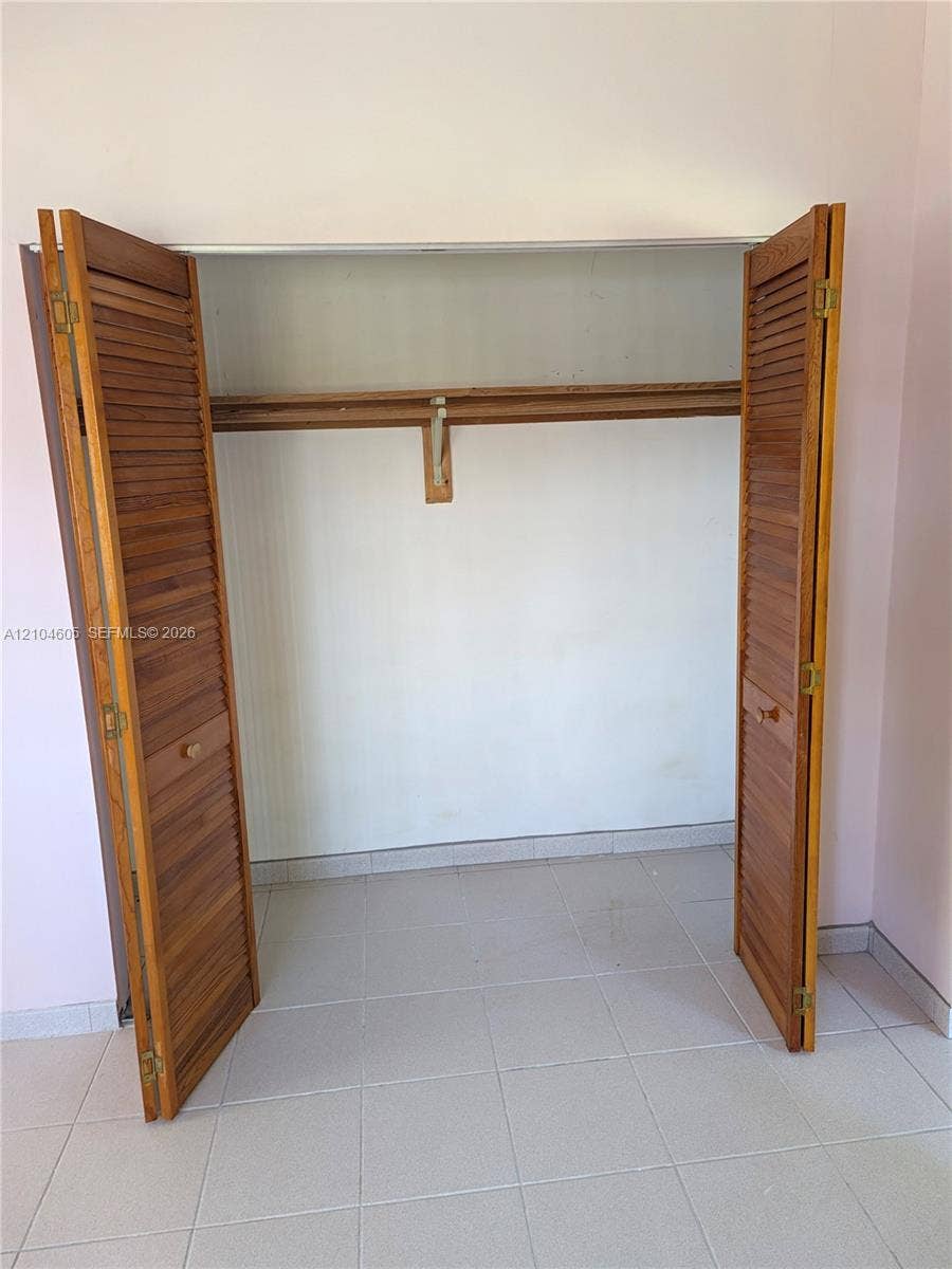 Storage space featuring bi-fold wooden louvered doors and a built-in shelf