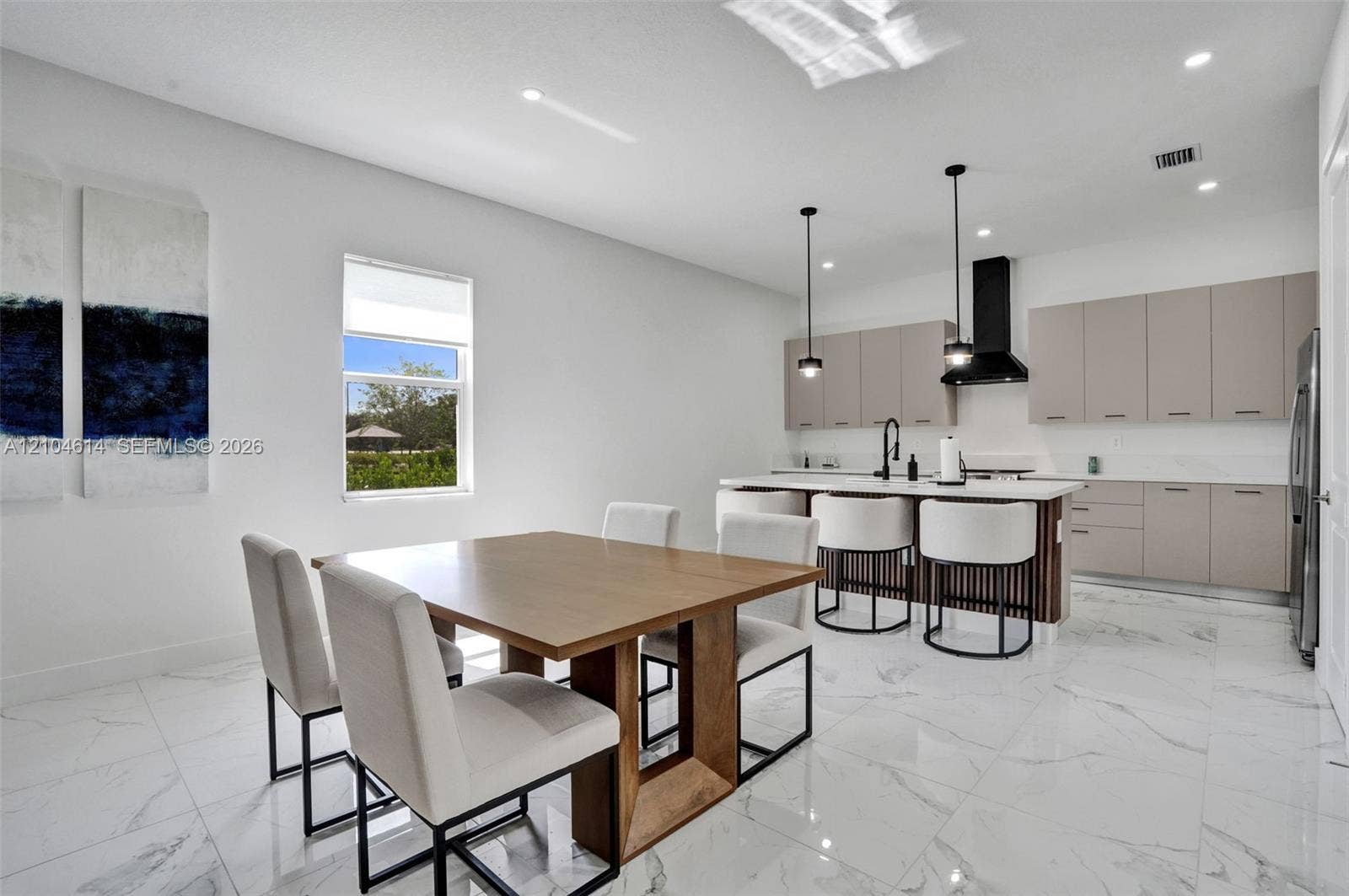 12240 SW 44th Court, Davie, FL 33330 Open-concept living space featuring a modern kitchen with a large island, sleek cabinetry, and pendant lighting