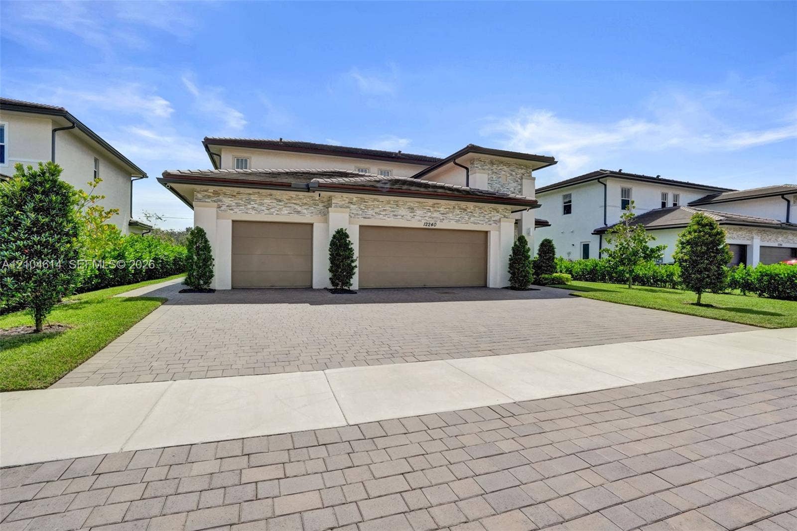 12240 SW 44th Court, Davie, FL 33330 Exterior featuring a multi-car paver driveway, stone facade accents, and mature landscaping