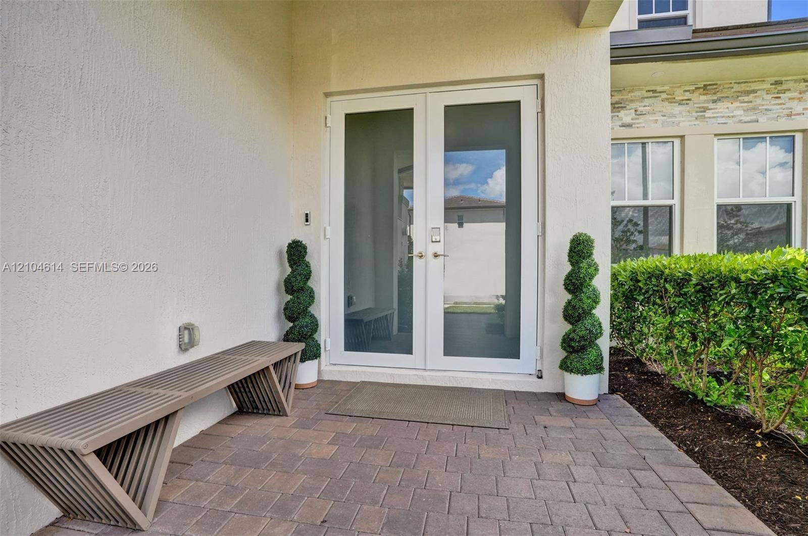 12240 SW 44th Court, Davie, FL 33330 Double glass-paneled entry doors, brick paver patio, stucco exterior, and manicured landscaping