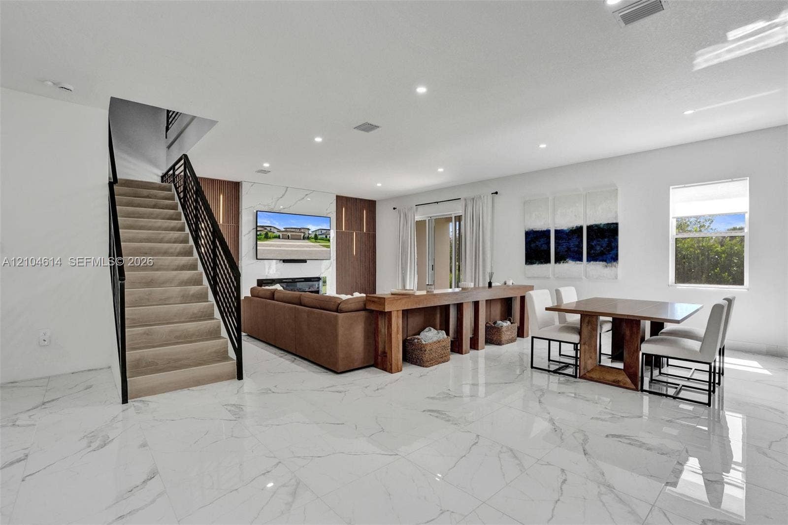12240 SW 44th Court, Davie, FL 33330 Spacious living area featuring polished tile flooring, recessed lighting, a modern fireplace, and a contemporary staircase with metal railings