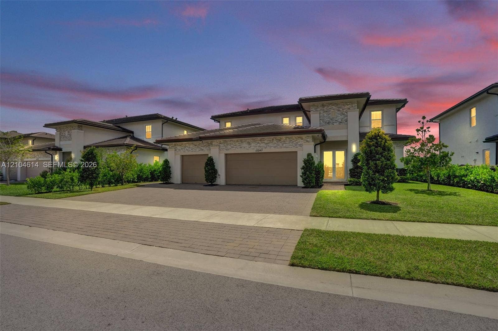 12240 SW 44th Court, Davie, FL 33330 Stucco exterior with stone accents, tile roof, dual garage doors, paved driveway, and established landscaping