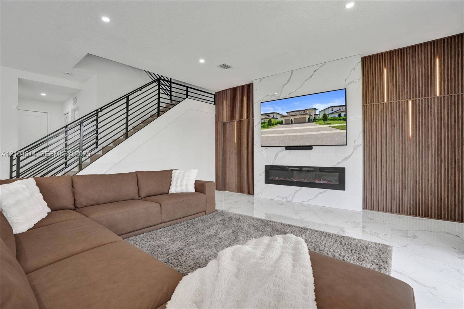 12240 SW 44th Court, Davie, FL 33330 Integrated fireplace with a white marbled look accent wall, recessed lighting, wood-finish paneling with vertical lighting elements, and sleek metal stair railing