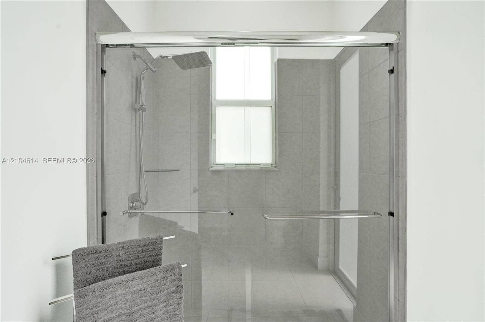 12240 SW 44th Court, Davie, FL 33330 Frameless glass shower enclosure featuring a rainfall showerhead and integrated window