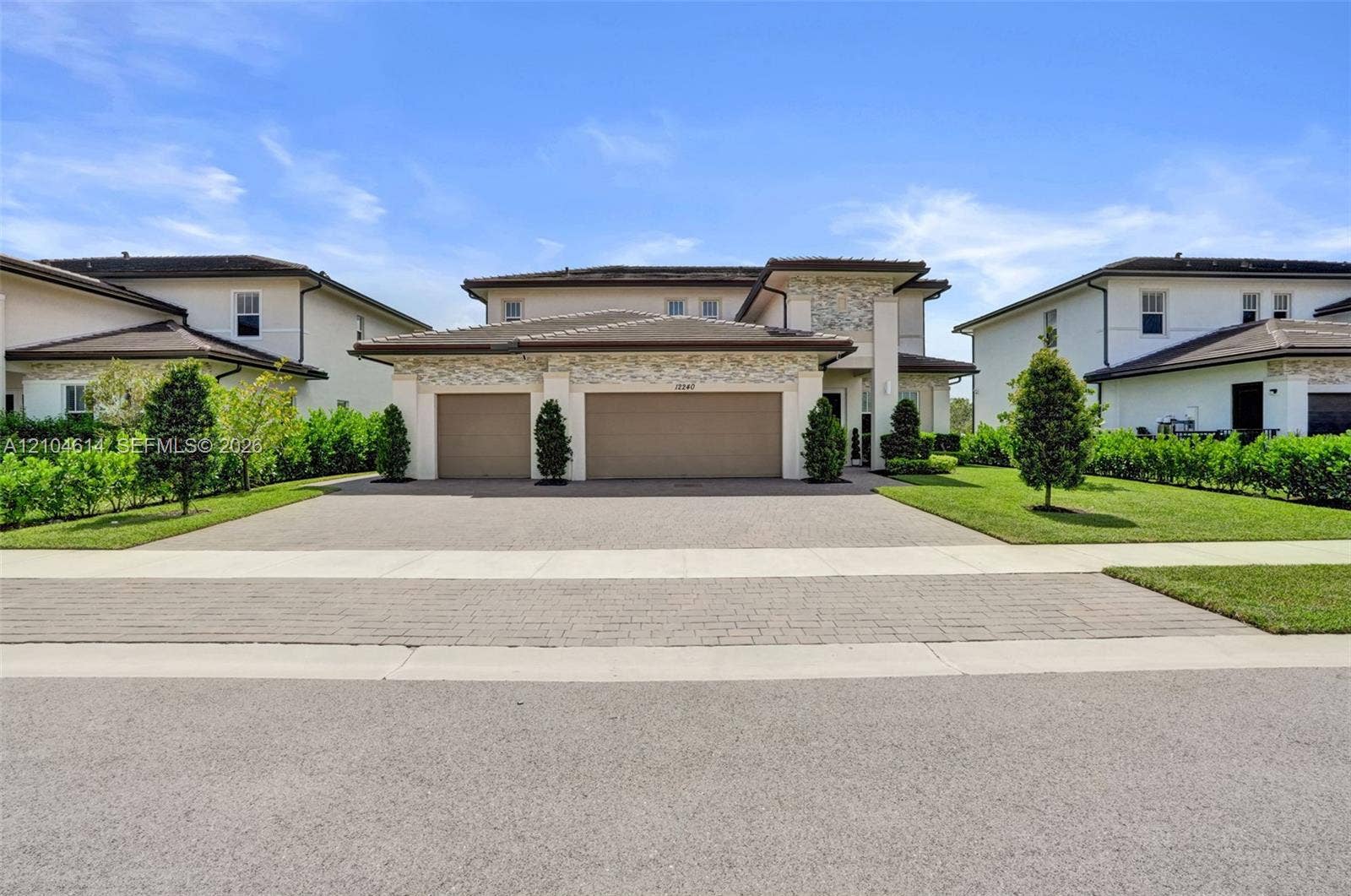 12240 SW 44th Court, Davie, FL 33330 Contemporary stucco and stone-clad exterior with a two-car garage and a paved driveway