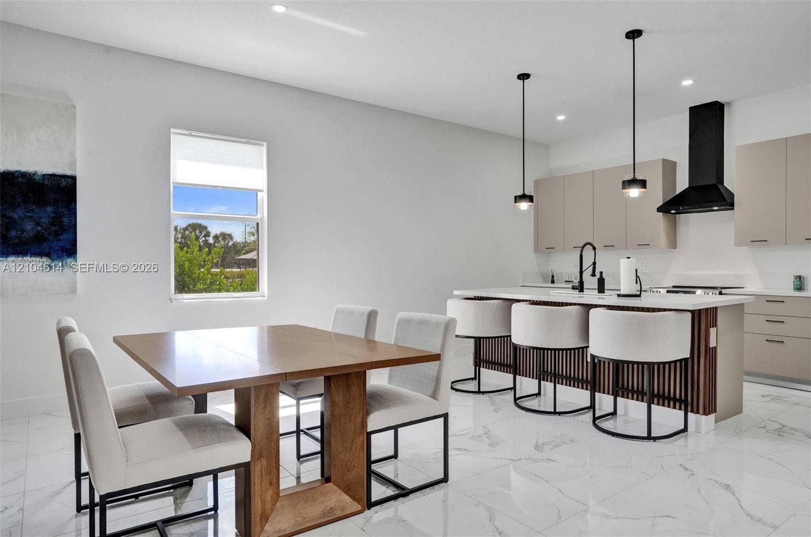 12240 SW 44th Court, Davie, FL 33330 Open-concept living space featuring a modern kitchen with an island, sleek pendant lighting, a contemporary range hood, and light-toned cabinetry