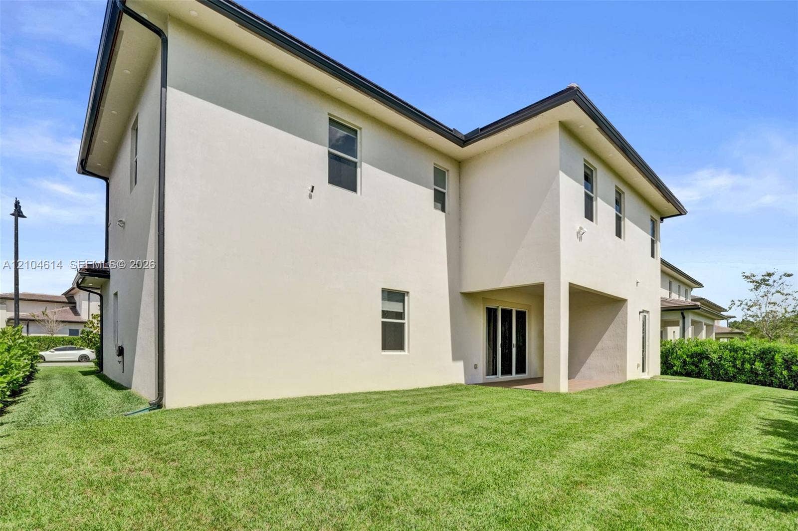12240 SW 44th Court, Davie, FL 33330 Two-story stucco exterior featuring multiple windows, a covered patio, and a sliding glass door