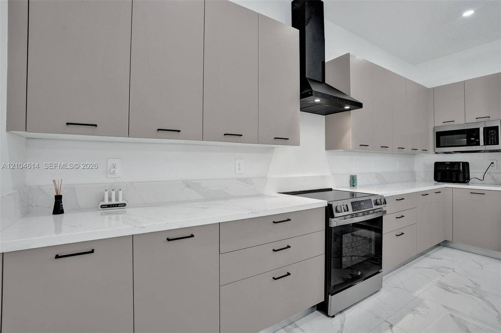 12240 SW 44th Court, Davie, FL 33330 Contemporary kitchen featuring light gray cabinetry, white countertops, stainless steel appliances, and a black range hood