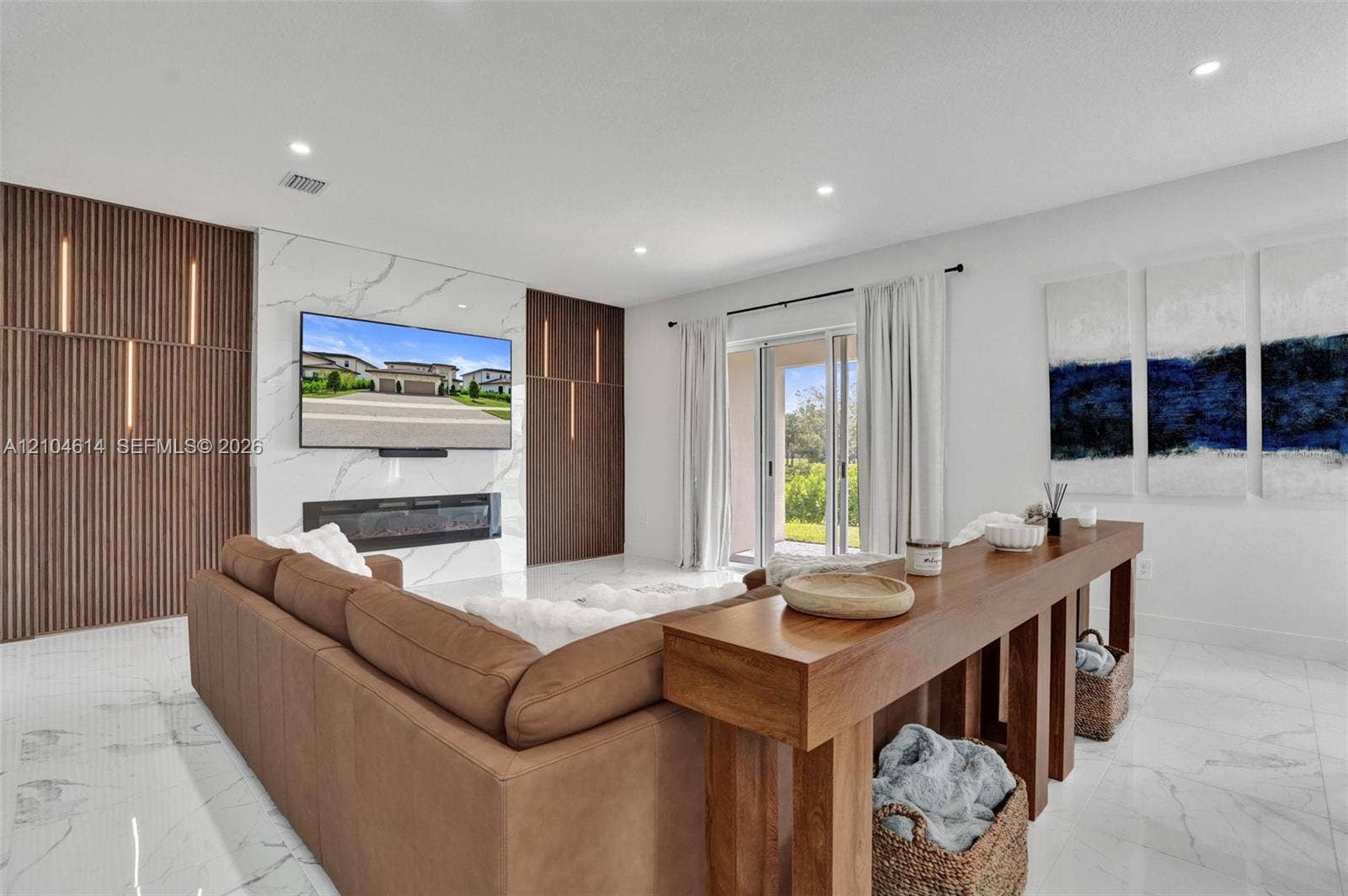 12240 SW 44th Court, Davie, FL 33330 Spacious living area featuring large format floor tiling, a decorative electric fireplace, and a striking accent wall with integrated vertical lighting