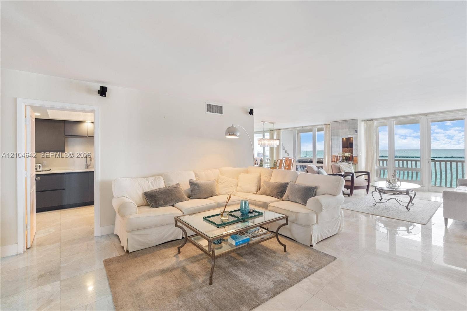 Open-concept living space featuring polished tile flooring, floor-to-ceiling windows, and direct access to a balcony with ocean exposure