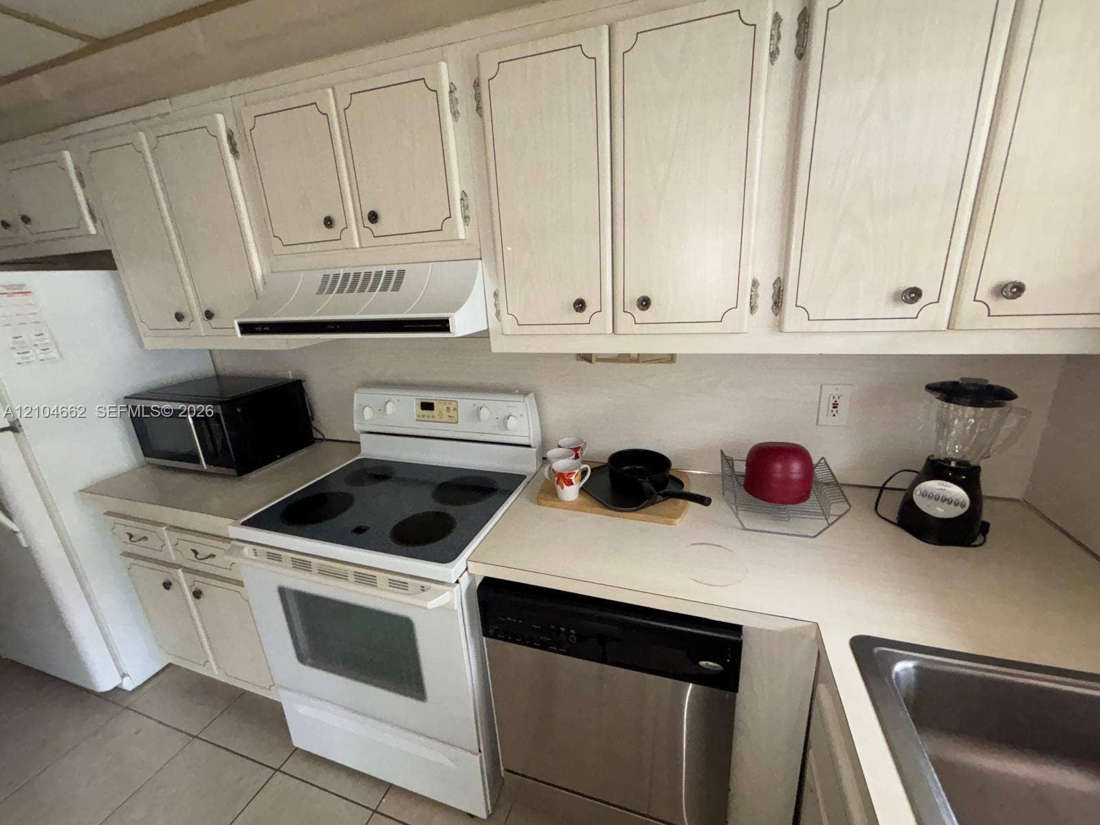 180 NE 12th Avenue, #12A, Hallandale Beach, Hallandale Beach, FL 33009 White cabinetry, light-toned countertops, white range with overhead vent, and a stainless steel dishwasher