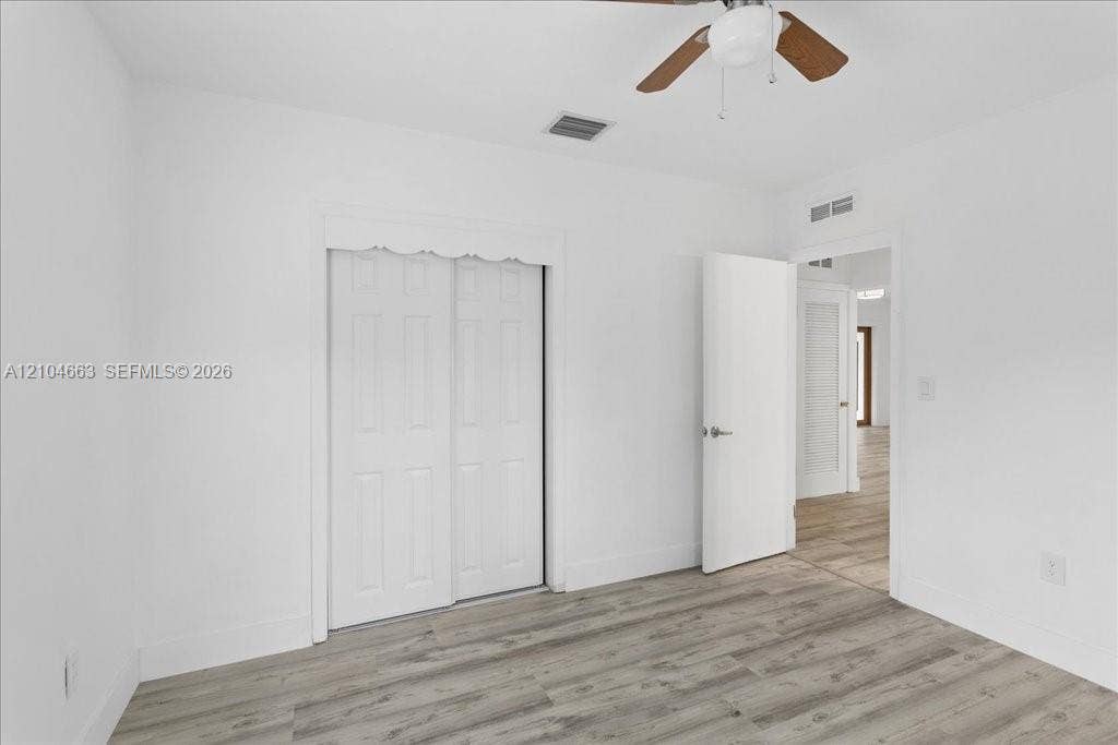 305 NW 111th Street, Miami Shores, FL 33168 Room featuring wood-finish flooring, a ceiling fan with integrated lighting, and a dual-panel sliding closet door
